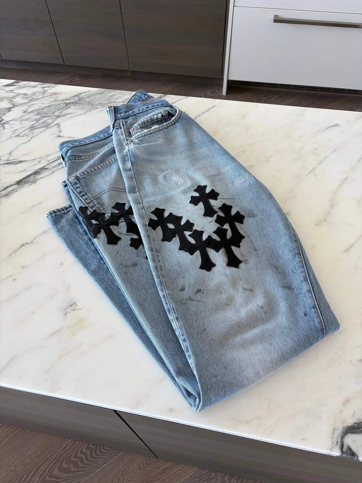 Folded blue jeans with black cross patches